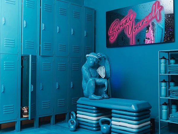 Turquoise lockers, sculpture, weights and a neon mirror in the installation